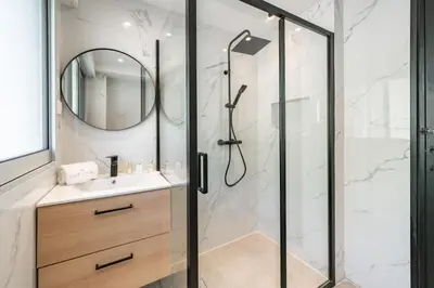 a bathroom with a shower with a sink and a mirror at Charming bright studio with spacious outdoor area in Cannes