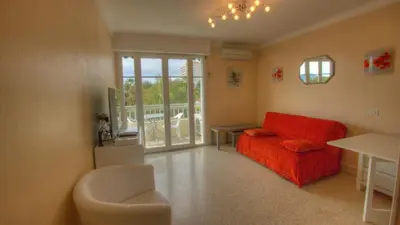 a living room with a red couch and a table at Studio 3 étoiles Vue mer 150m Plages Parking Clim WIFI in Cannes