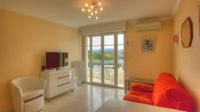 a living room with a red couch and a television at Studio 3 étoiles Vue mer 150m Plages Parking Clim WIFI in Cannes