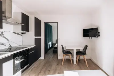 a white kitchen with a table and two chairs at Cozy 2-bedroom apartment - Close to Palais, Croisette in Cannes