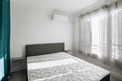 a bed in a room with a large window at Cozy 2-bedroom apartment - Close to Palais, Croisette in Cannes