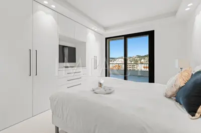 a white bedroom with a large bed and a television at REF 2027 - Cannes Centre - Apartment for Rent in Cannes