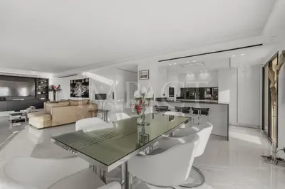 a kitchen and living room with a glass table and white chairs at REF 2027 - Cannes Centre - Apartment for Rent in Cannes