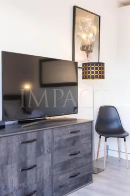 a television on a wooden dresser with a black chair at Cannes Croisette 2034 - Studio for rent in Cannes