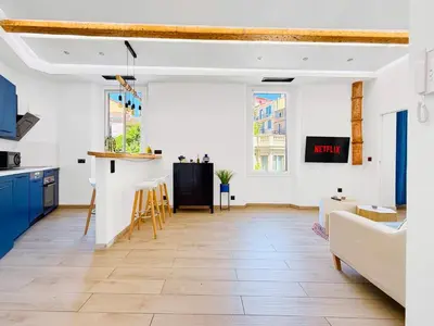 a kitchen and living room with white walls and blue cabinets at Nova - near sea and beaches in Cannes