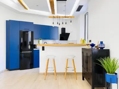 a kitchen with blue cabinets and a black refrigerator at Nova - near sea and beaches in Cannes