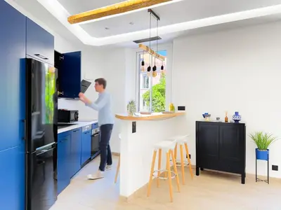 a man standing in a kitchen with blue cabinets at Nova - near sea and beaches in Cannes