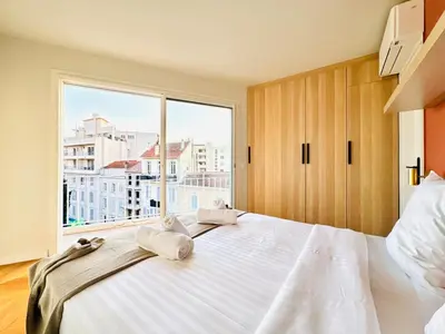 a bedroom with a large bed with a large window at Le Clemenceau - Cannes Mer Belle Vue in Cannes