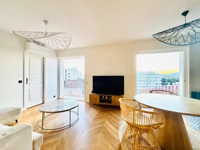 a living room with a table and a tv at Le Clemenceau - Cannes Mer Belle Vue in Cannes