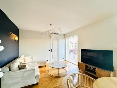 a living room with a couch and a tv at Le Clemenceau - Cannes Mer Belle Vue in Cannes