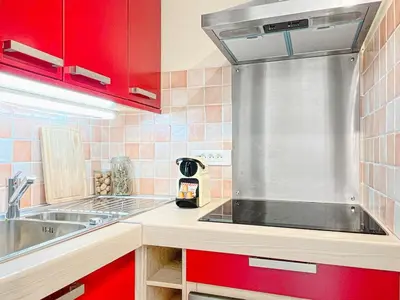 a kitchen with red cabinets and a stainless steel sink at Cannes Montfleury - Comfortable accommodation Center in Cannes