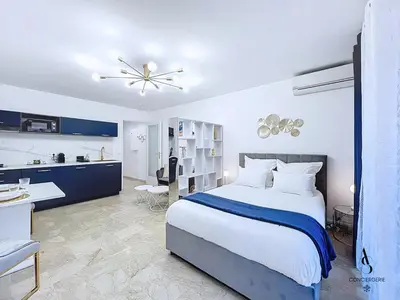 a bedroom with a large bed and a kitchen at Le Gatsby - 2 pers - 10 min Palais - AC in Cannes