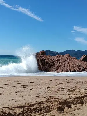 a wave crashing on a beach with a rock at Cannes superbe appt 3 pces Wi-Fi Clim Piscine Vue sur les îles et les Paquebots in Cannes