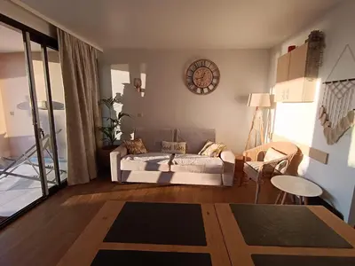 a living room with a couch and a clock on the wall at Cannes superbe appt 3 pces Wi-Fi Clim Piscine Vue sur les îles et les Paquebots in Cannes