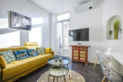 a living room with a yellow couch and a tv at Le Mimosa in Cannes