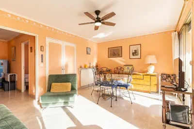 a living room with a ceiling fan and a table and chairs at La Terrasse du Riou – Soleil Plages à Cannes in Cannes