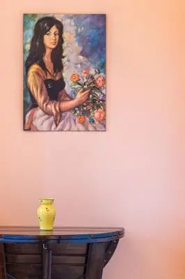 a painting of a woman holding flowers on a wall at La Terrasse du Riou – Soleil Plages à Cannes in Cannes