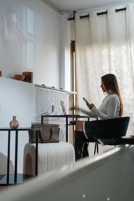 a woman sitting at a table looking at her cell phone at StudioLuxCannes - Suite premium avec baignoire à Cannes, plage à 2 min et Palais des Festivals in Cannes