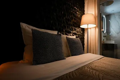 a bedroom with a bed with pillows and a lamp at StudioLuxCannes - Suite premium avec baignoire à Cannes, plage à 2 min et Palais des Festivals in Cannes