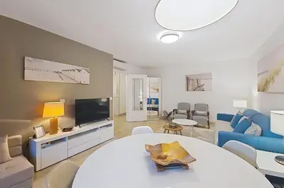 a living room with a white table and a tv at HENRI CAMILLE RE - Passy1 -Beautiful one bedroom swimming pool and parking in Cannes