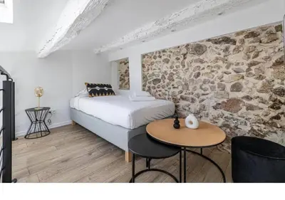 a bedroom with a bed and a table and a stone wall at Bright Apartment Mezzanine in the Heart of Suquet in Cannes