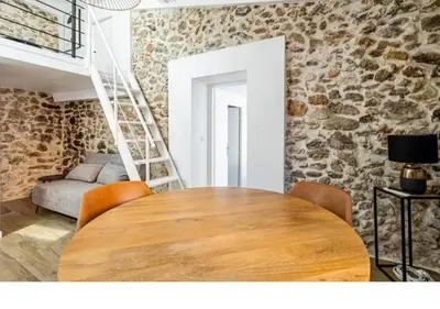 a wooden table in a room with a stone wall at Bright Apartment Mezzanine in the Heart of Suquet in Cannes
