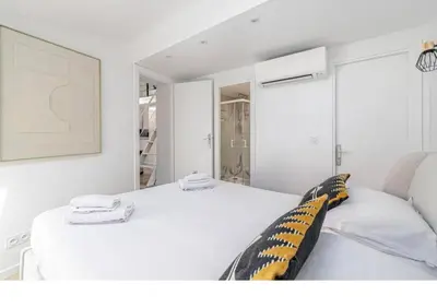 a white bedroom with a bed and a mirror at Bright Apartment Mezzanine in the Heart of Suquet in Cannes