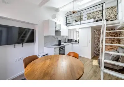 a kitchen with a wooden table and chairs in a room at Bright Apartment Mezzanine in the Heart of Suquet in Cannes