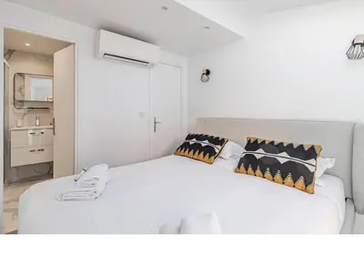 a bedroom with a white bed with pillows on it at Bright Apartment Mezzanine in the Heart of Suquet in Cannes