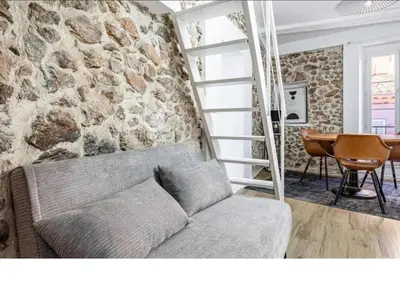 a living room with a couch and a stone wall at Bright Apartment Mezzanine in the Heart of Suquet in Cannes