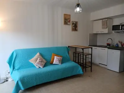 a blue couch in a living room with a kitchen at Studio LE MEDITERRANEE in Cannes
