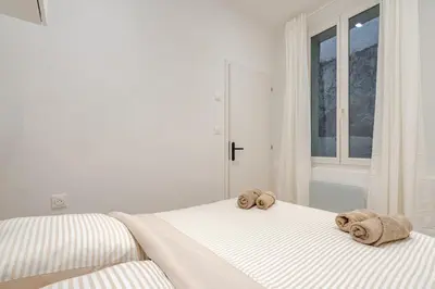 a white bedroom with two towels on a bed at Élégant 2P Rue Meynadier Proche du Palais et des plages in Cannes