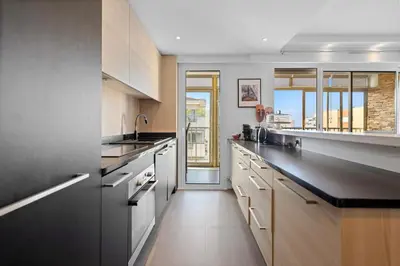 a large kitchen with white cabinets and black counter tops at 11 MADRID - Splendid one-bedroom apartment near Croisette in Cannes