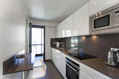 a kitchen with white cabinets and a black counter top at 2 chambres au cœur de Cannes - Croisette et plages à 1 min in Cannes