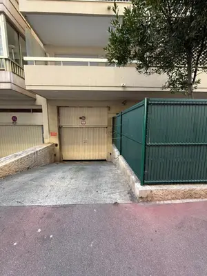 a building with a green gate and a garage at Carlton Exclusive - Elégant T2 au coeur de la Croisette in Cannes