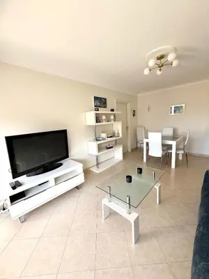 a living room with a flat screen tv and a table at Carlton Exclusive - Elégant T2 au coeur de la Croisette in Cannes