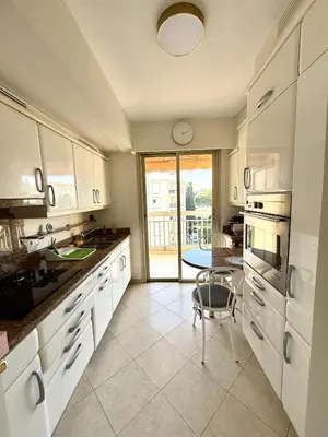 a kitchen with white cabinets and a table in it at Carlton Exclusive - Elégant T2 au coeur de la Croisette in Cannes