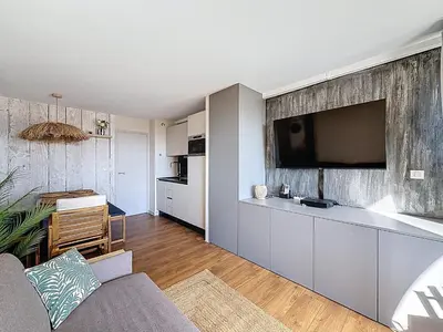 a living room with a large tv on a wall at Bleu Azur - 2 piscines & plage à 200m in Cannes