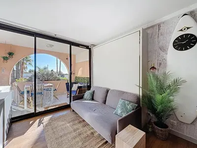 a living room with a couch and a clock on the wall at Bleu Azur - 2 piscines & plage à 200m in Cannes