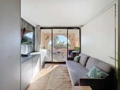 a living room with a couch and a table at Bleu Azur - 2 piscines & plage à 200m in Cannes