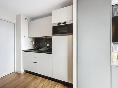a kitchen with white cabinets and a refrigerator at Bleu Azur - 2 piscines & plage à 200m in Cannes