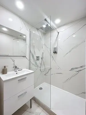 a white bathroom with a shower and a sink at Bleu Azur - 2 piscines & plage à 200m in Cannes