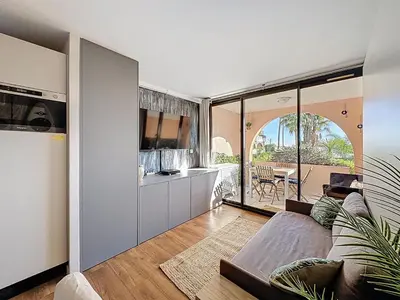 a living room with a couch and a table at Bleu Azur - 2 piscines & plage à 200m in Cannes