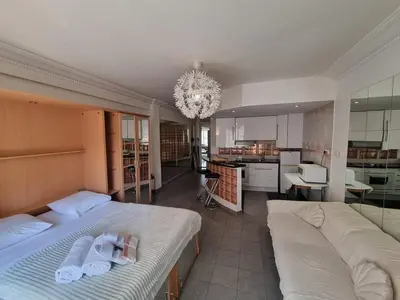 a bedroom with two beds and a kitchen with a chandelier at Charming Studio near Croisette in Cannes