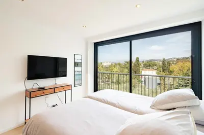 two beds in a bedroom with a large window at COZYSTAY 1700 -Luxury 3-Bedroom Apartment with Terrace & Sea View in Cannes in Cannes