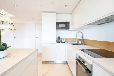 a white kitchen with white cabinets and a sink at COZYSTAY 1700 -Luxury 3-Bedroom Apartment with Terrace & Sea View in Cannes in Cannes