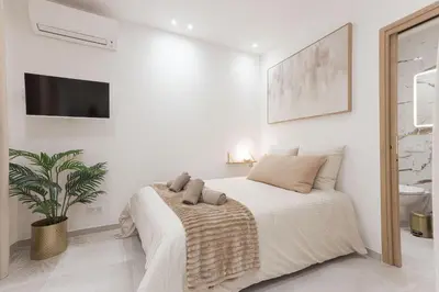 a white bedroom with a bed and a tv on the wall at Studio Méro by Halldis in Cannes