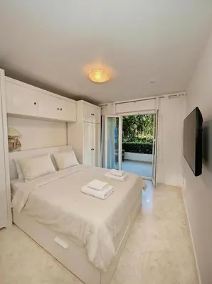a white bedroom with a large bed and a television at Long Beach Apartment Cannes in Cannes