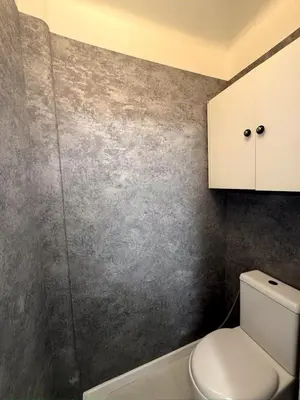 a bathroom with a toilet and a gray wall at Long Beach Apartment Cannes in Cannes