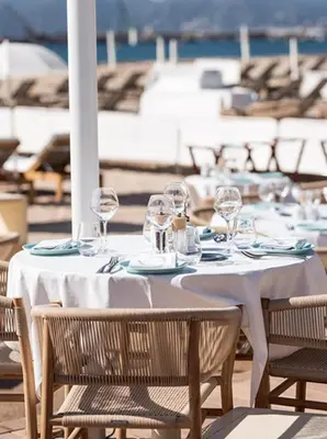 a table with glasses and plates and chairs on a patio at Long Beach Apartment Cannes in Cannes
